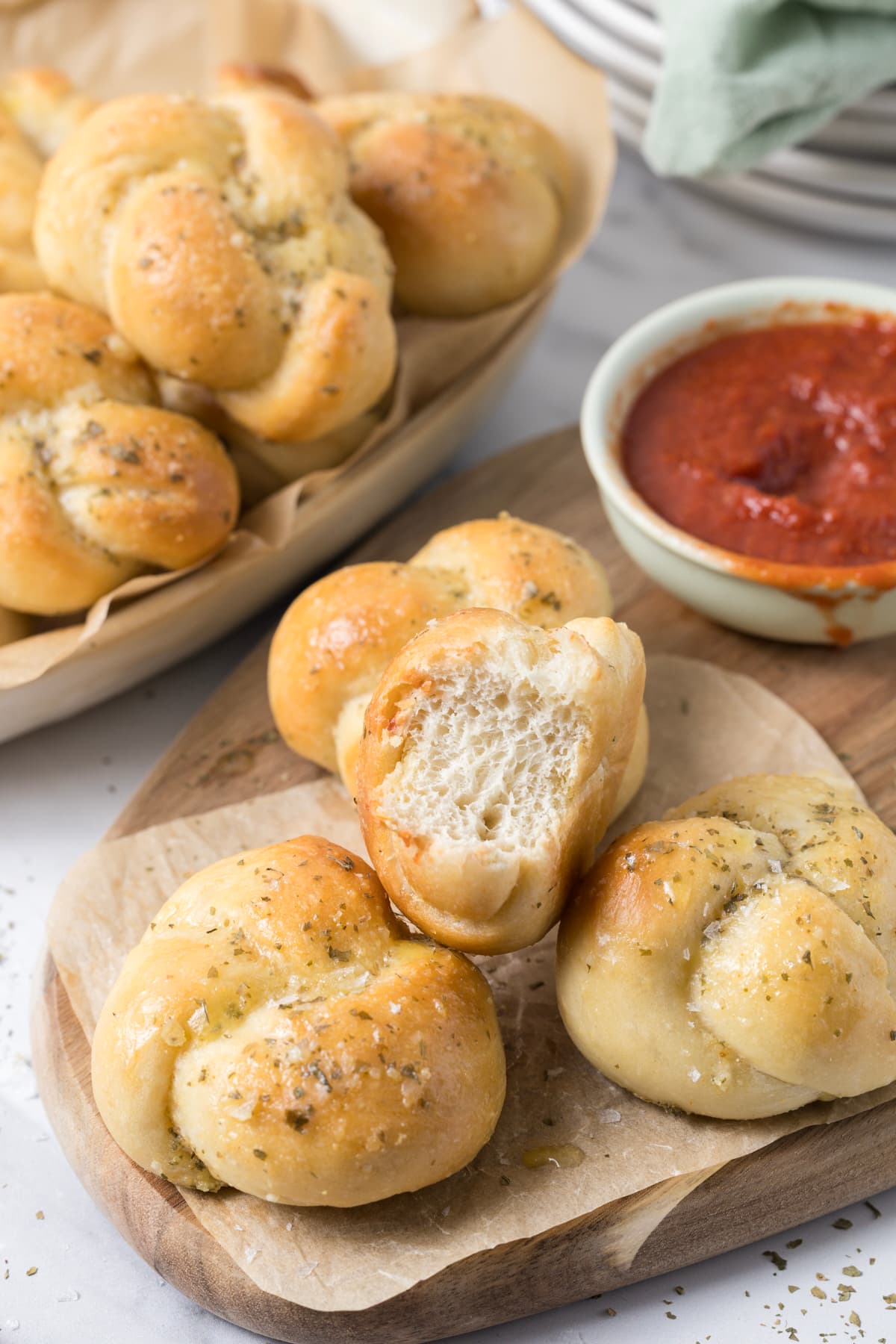 Sourdough discard garlic knots on a serving tray with one missing a bite to show inside texture.