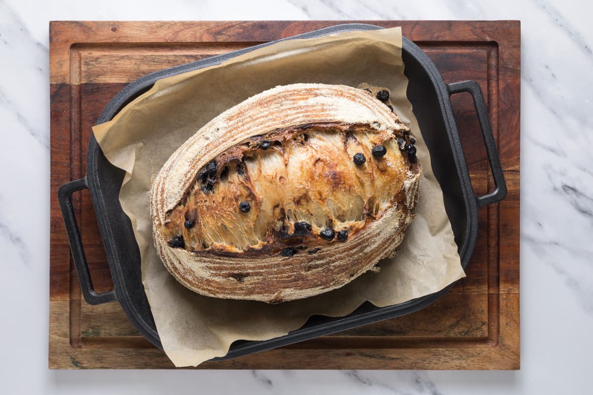 A finished loaf of sourdough lemon blueberry bread that has been taken out of the oven and is still sitting in a rectangle cast iron bread pan.