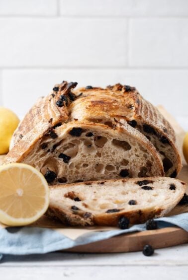 A sliced loaf of sourdough lemon blueberry bread on a cutting board ready for serving.