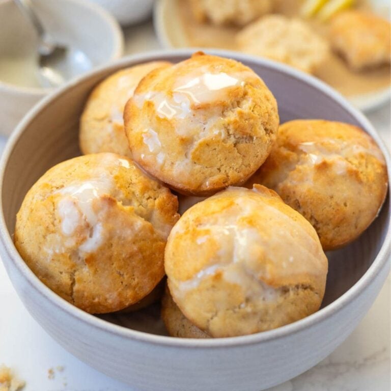 Bowl of sourdough lemon muffins topped with lemon glaze.