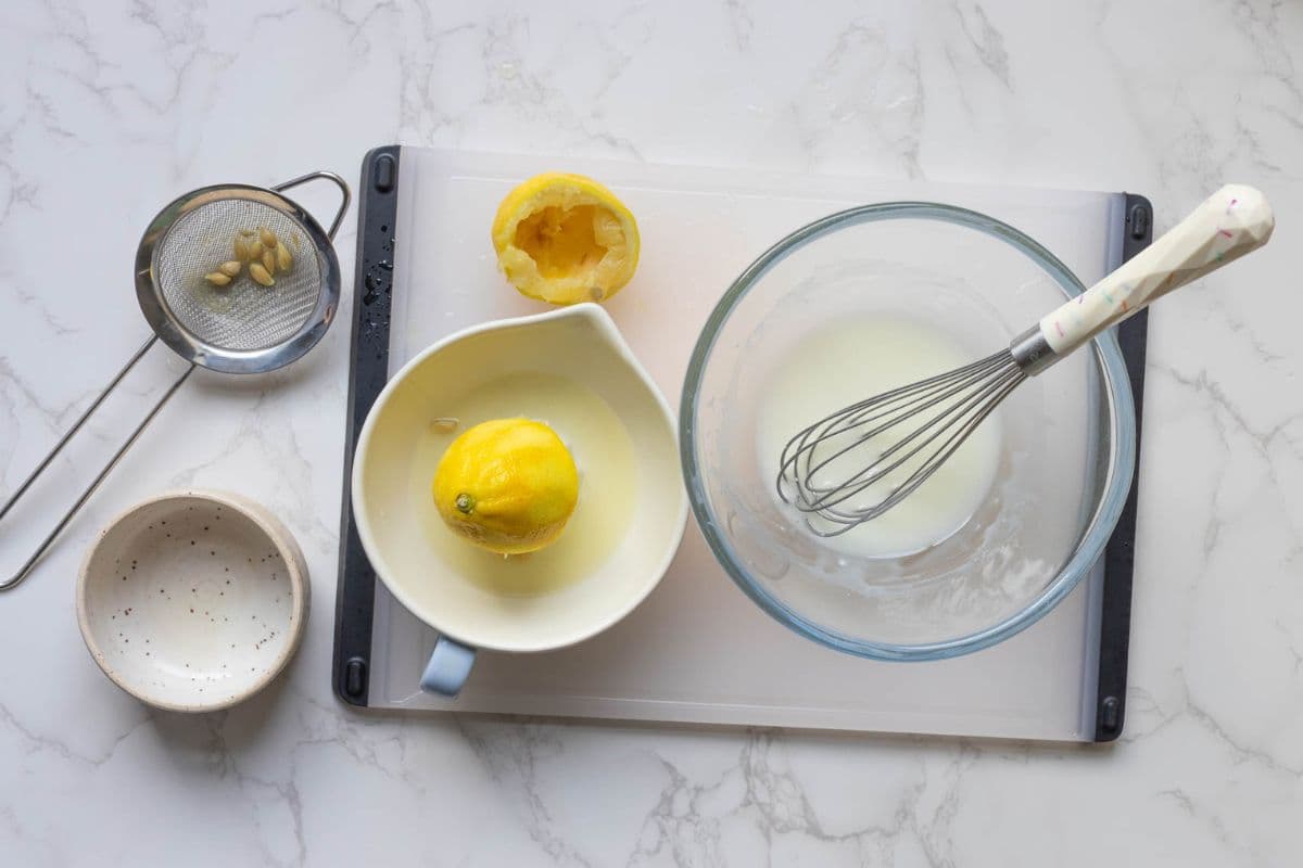 Fresh lemon juice being whisked with powdered sugar to make lemon glaze.