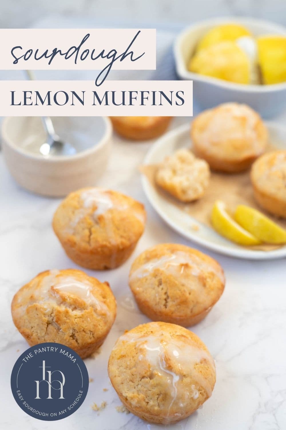 Sourdough lemon muffins with lemon glaze arranged on a countertop with lemon slices and text overlay for a Pinterest Pin.