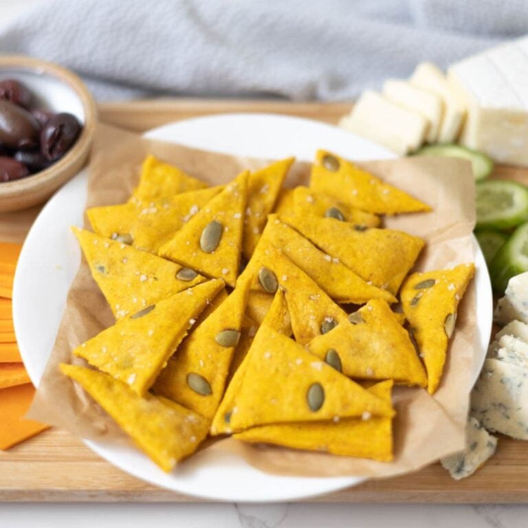 Close up of triangle shaped sourdough pumpkin crackers on a snack board.