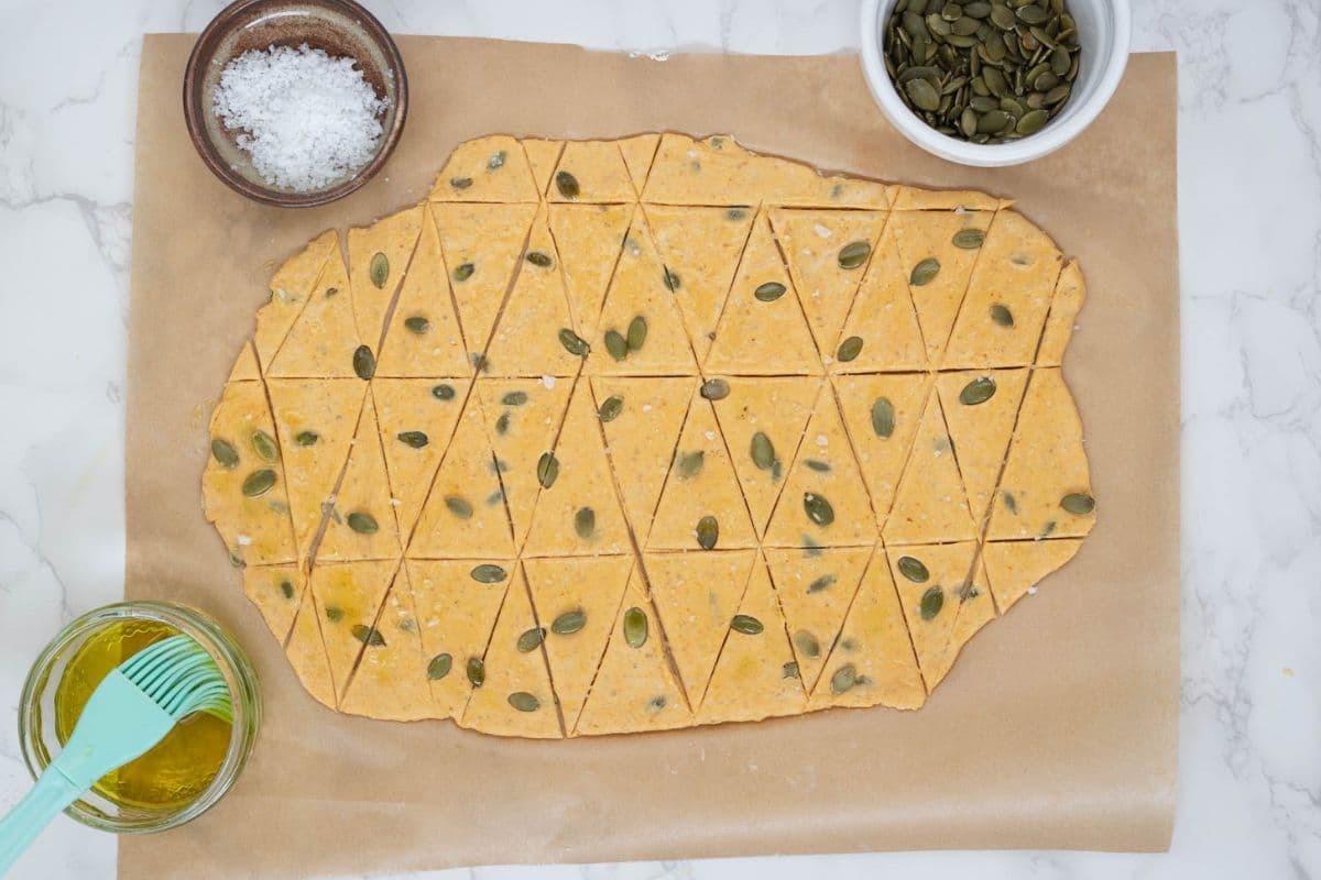 Rolled out dough cut into triangles to make sourdough pumpkin crackers.