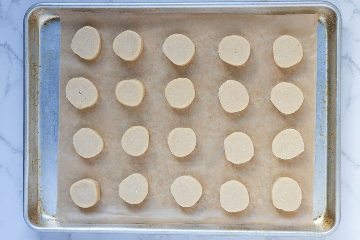 Sourdough shortbread cookie dough rounds on a parchment lined baking sheet ready to be baked.