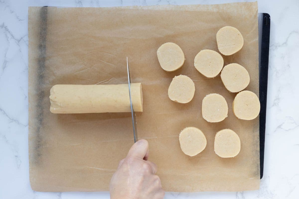 Cutting sourdough shortbread cookie dough log into cookie rounds.