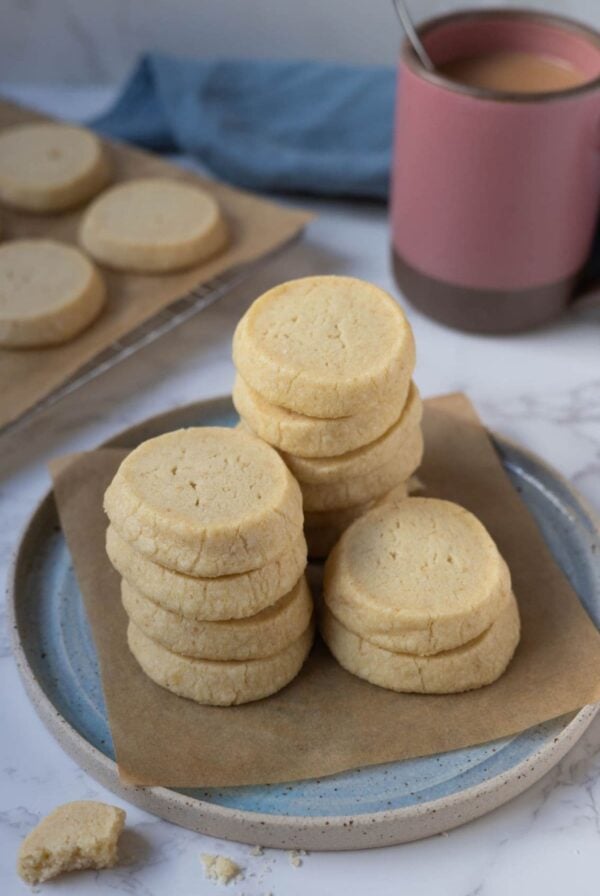 Sourdough shortbread cookies stacked on a plate for serving with a cup of tea.