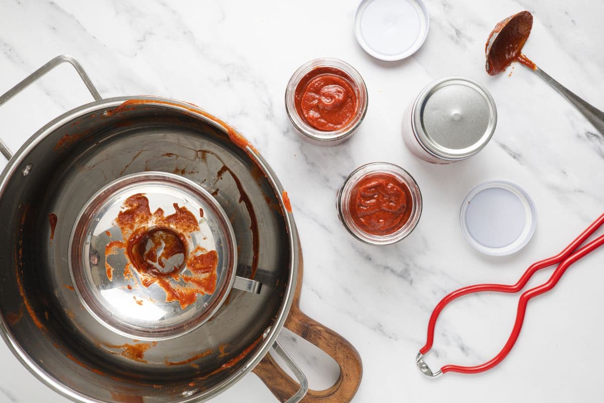 Funneling homemade ketchup into sterilized jars.