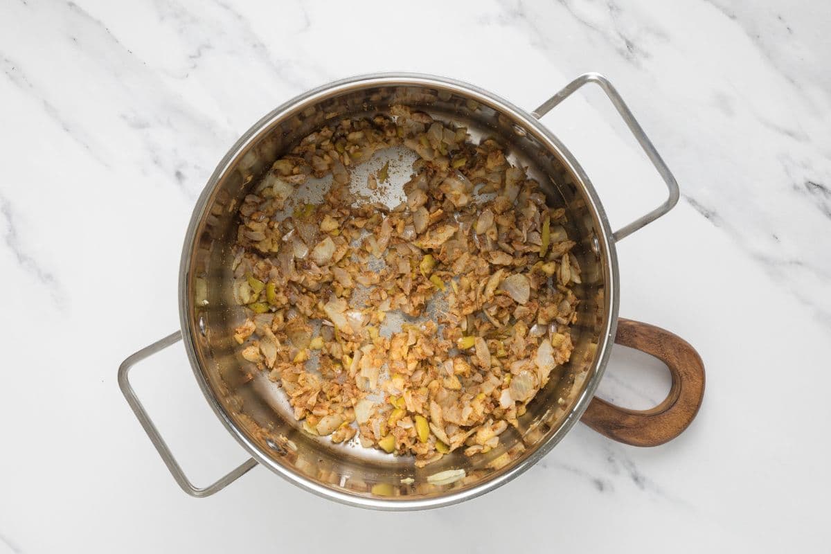 Cooking the onion, apple, and seasonings in a pot to make homemade ketchup.