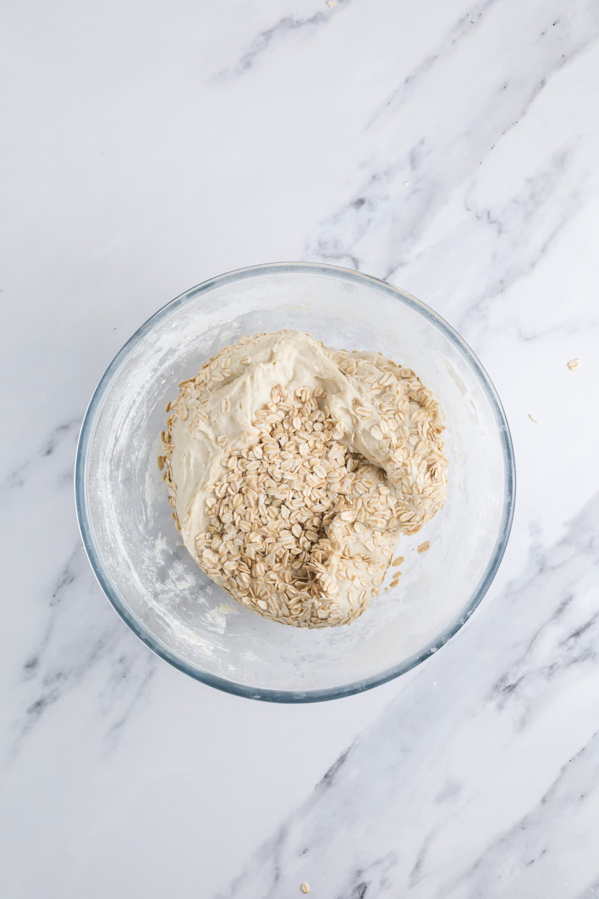 Adding more oats to the sourdough honey oat bread dough during stretch and folds.