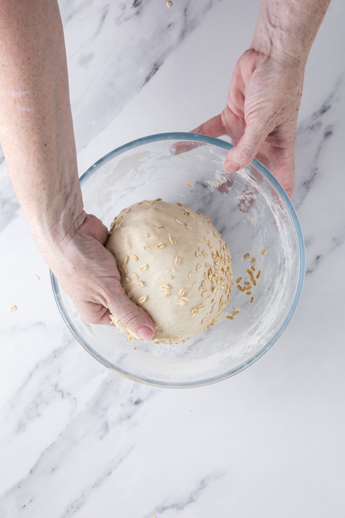 Forming a ball of dough to make sourdough honey oat bread.