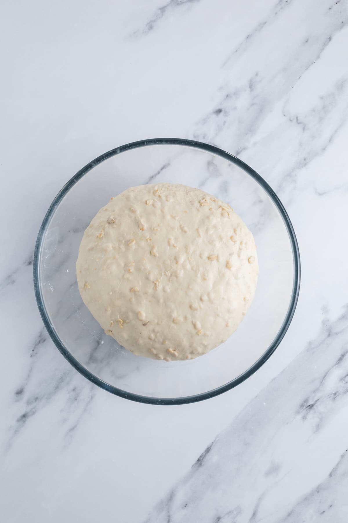 A ball of sourdough honey oat bread dough that has gone through fermentation to double in size.