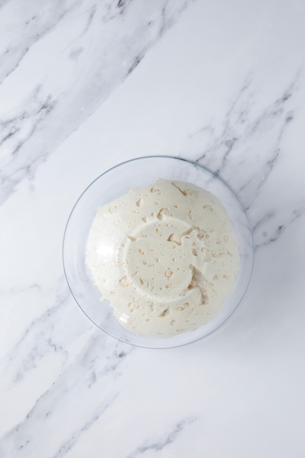 Turning mixing bowl over to place ball of fermented sourdough honey oat bread dough on the counter for shaping.