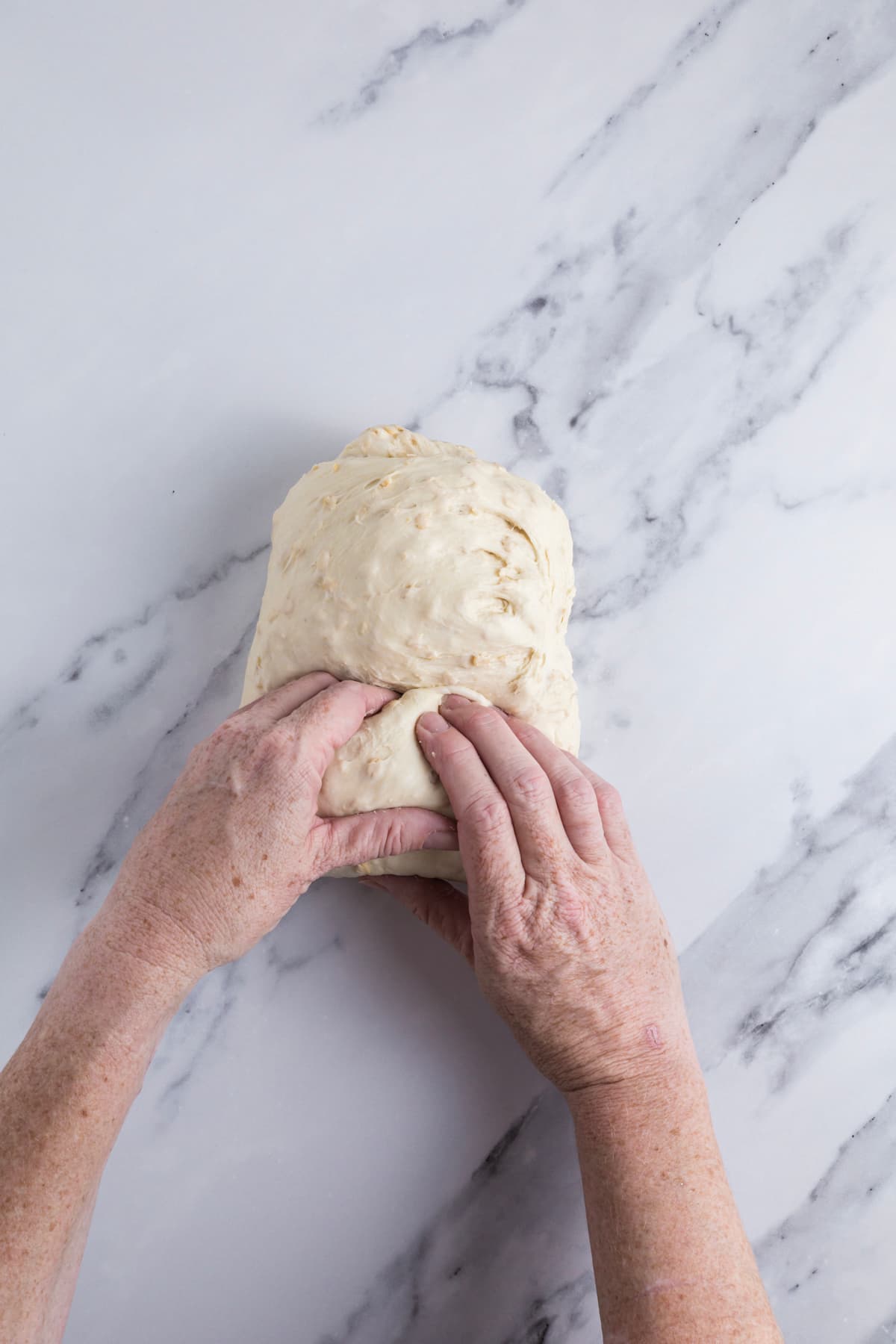 Rolling sourdough honey oat bread dough to place into banneton.