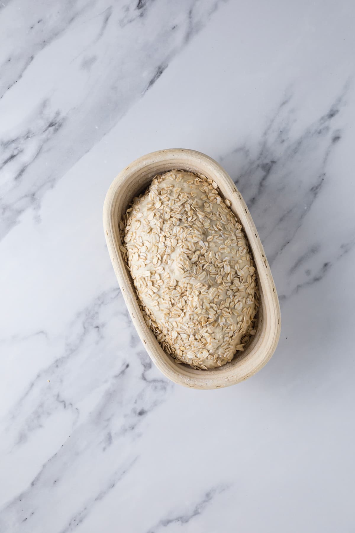Sourdough honey oat bread dough placed in banneton.