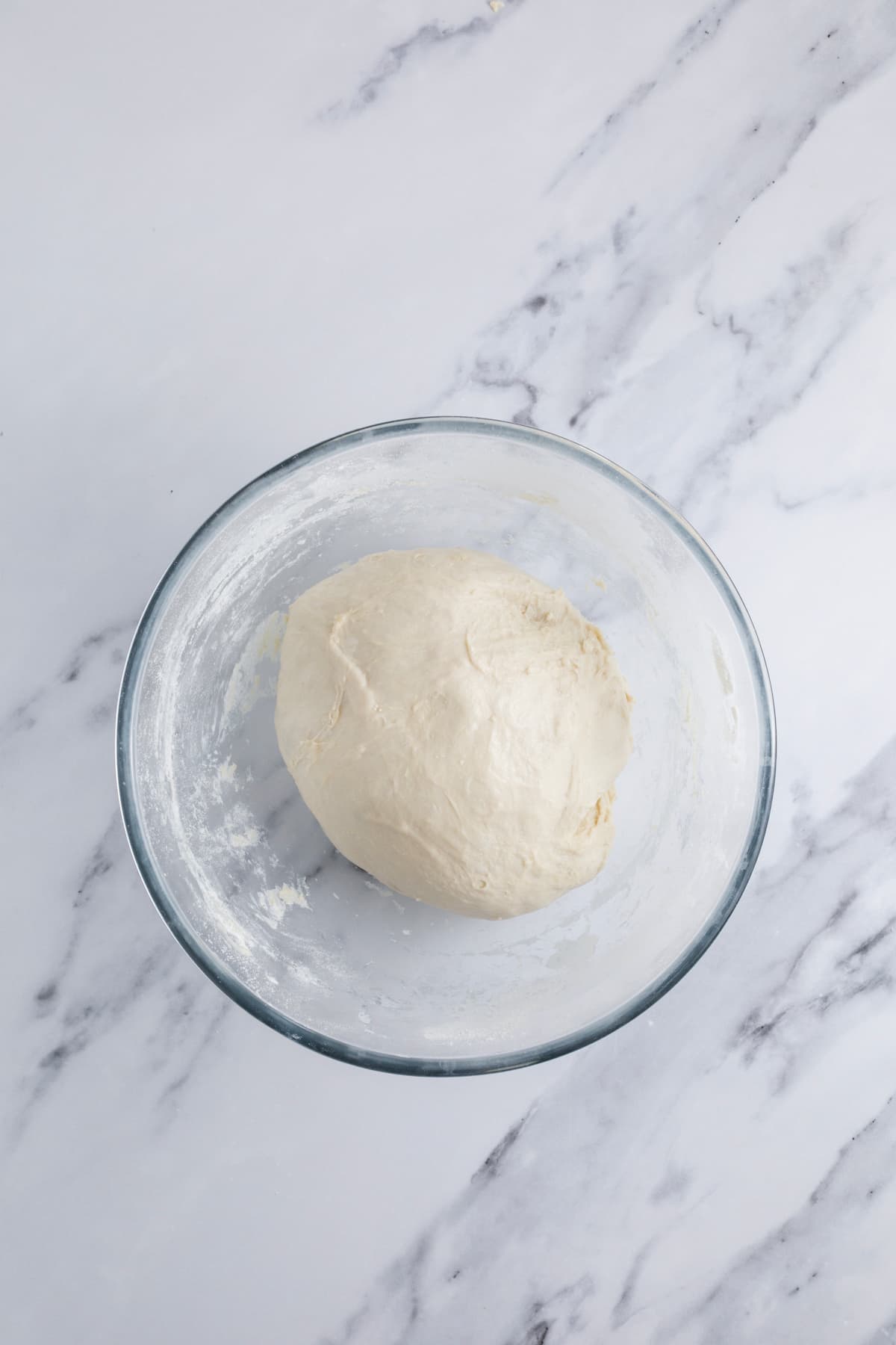 A smooth ball of sourdough honey oat bread dough in a glass mixing bowl.