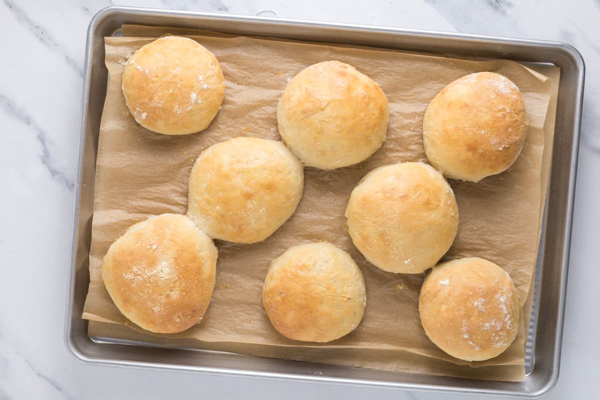 Fresh baked sourdough discard rolls on a parchment lined baking sheet.