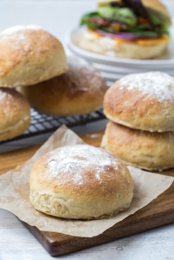 Sourdough discard rolls being used to make a sandwich with a sandwich in the background.