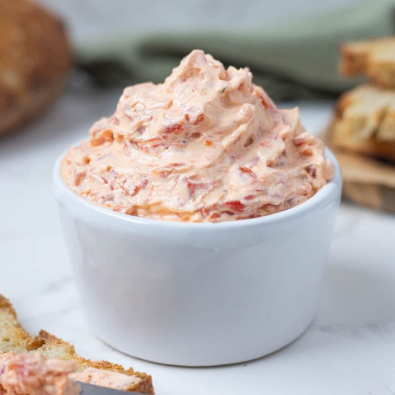 Close up of roasted red pepper cream cheese dip in a bowl showing creamy texture.