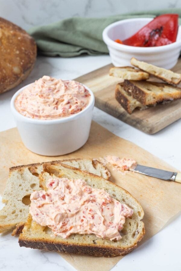 Roasted red pepper cream cheese dip spread on toasted sourdough bread slice.