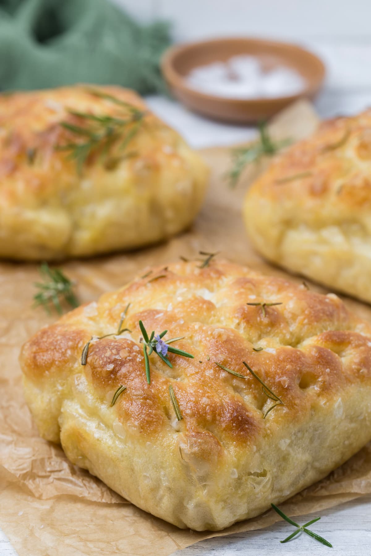 Close up of a loaf of simple sourdough focaccia bread with fresh rosemary leaves on top.
