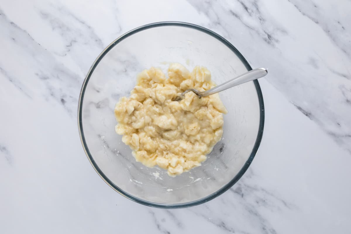 Mashed bananas in a glass bowl to make sourdough discard banana bread.