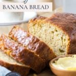A sliced loaf of sourdough discard banana bread being served with butter with text overlay on top for a Pinterest image.