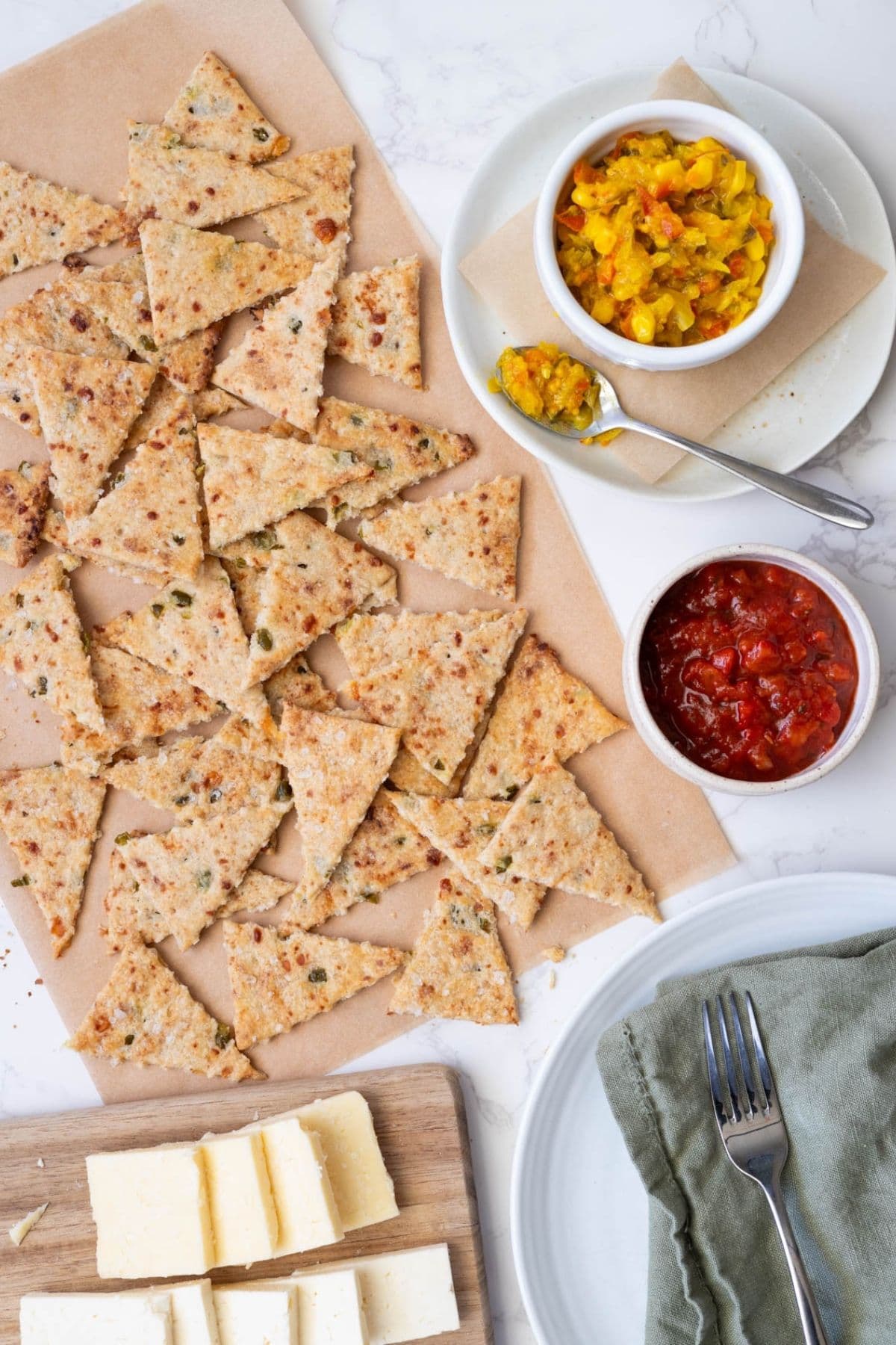 A grazing board of sourdough jalapeño cheddar crackers, relish and cheese on the counter.