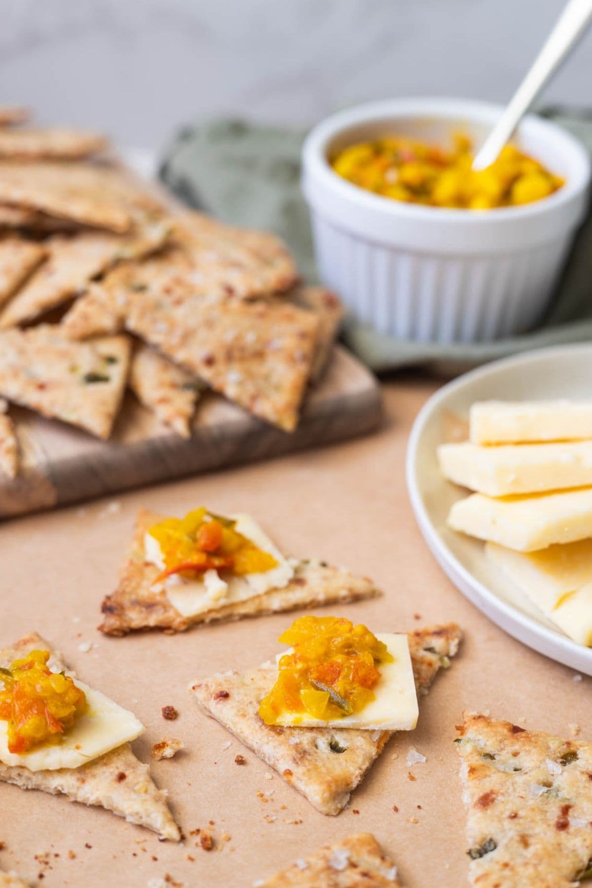 Sourdough jalapeño cheddar crackers with a slice of cheese and topped with corn relish for serving.