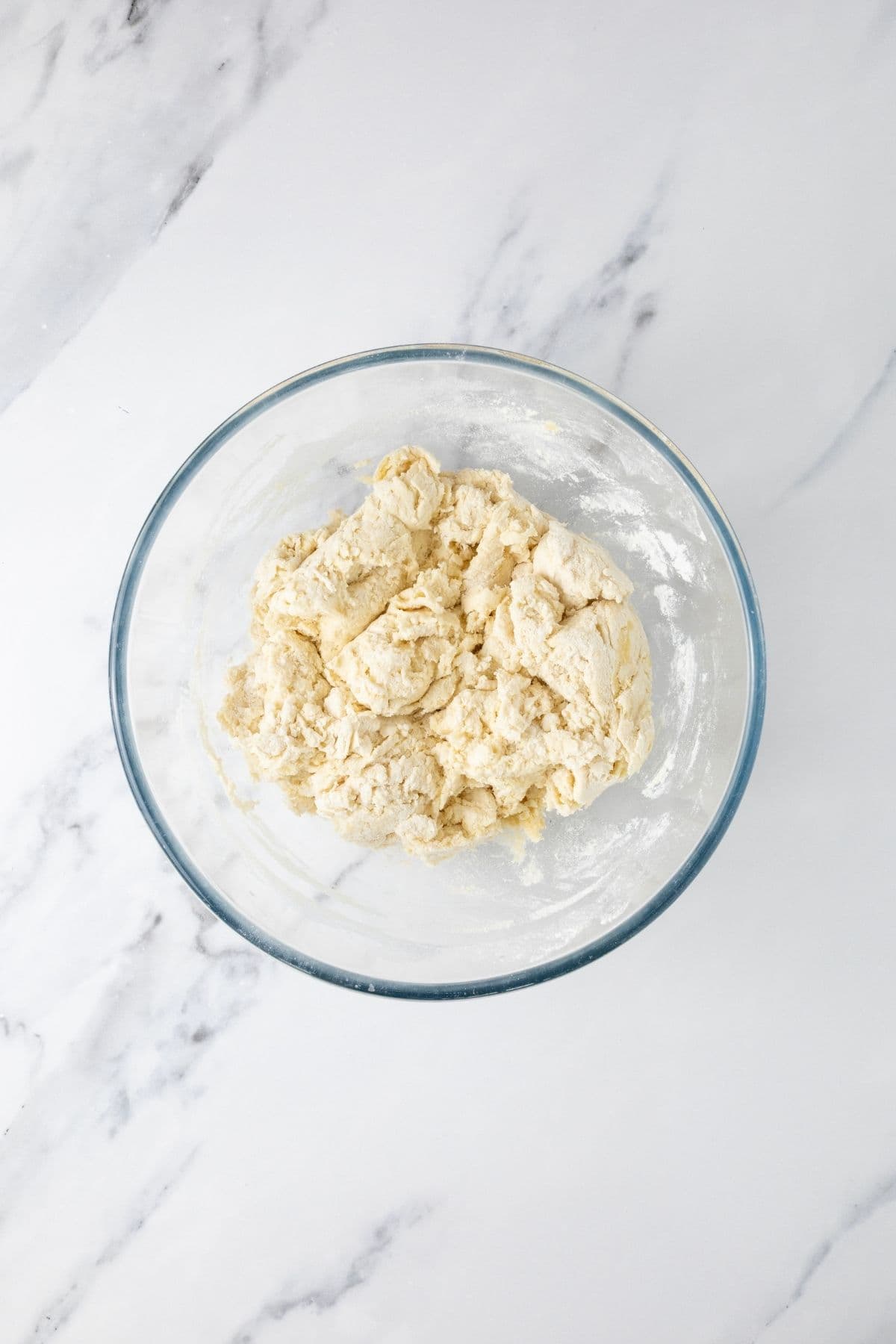 Mixed ingredients in a glass mixing bowl for sourdough parchment crackers.