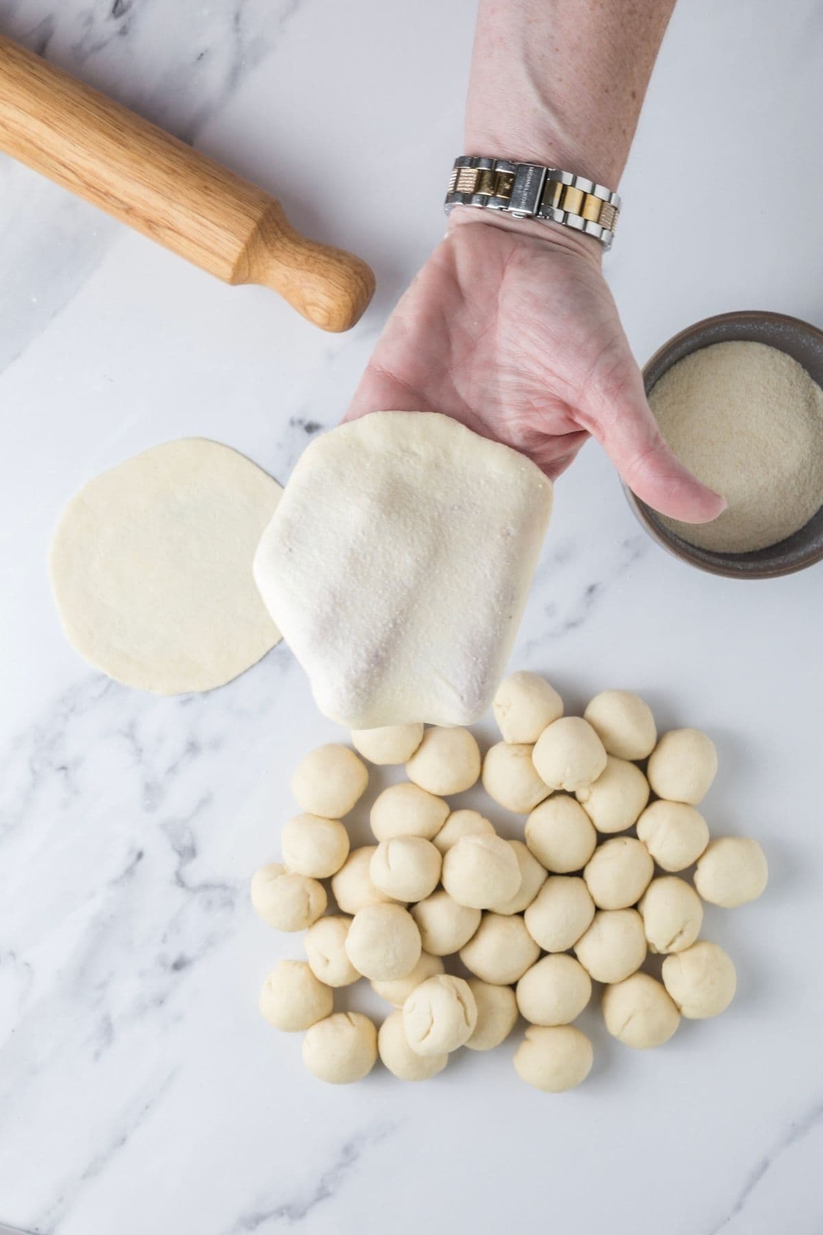 Rolling out the dough into flat rounds to make sourdough parchment crackers.