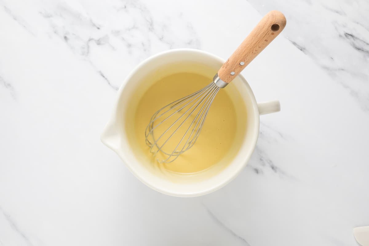 Whisking the wet ingredients in a bowl to make sourdough peach cobbler muffins.