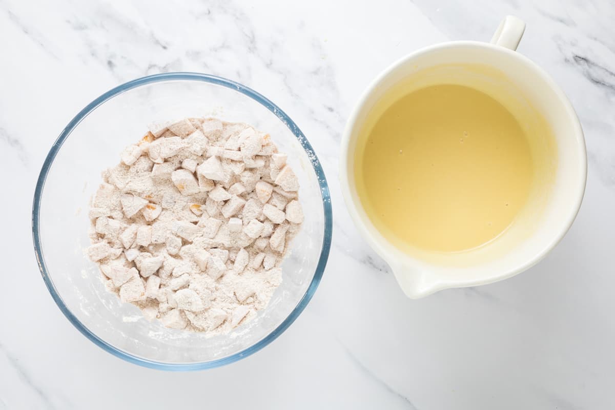 A bowl of dry ingredients next to a bowl of wet ingredients to make sourdough peach cobbler muffins.