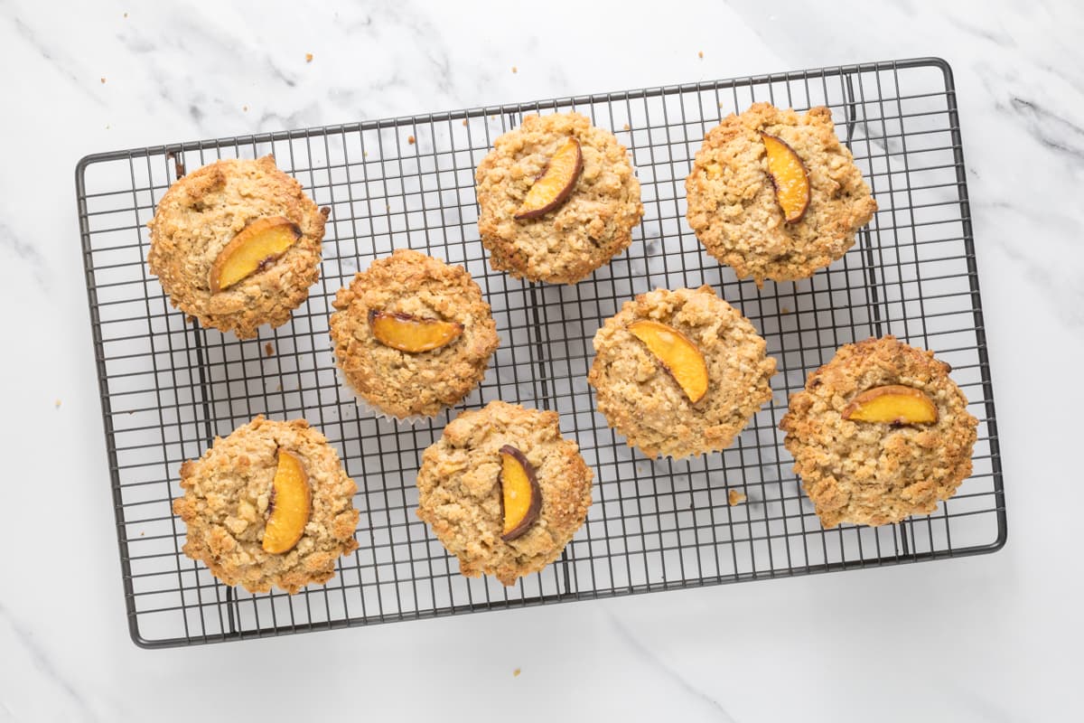 Fresh baked sourdough peach cobbler muffins cooling on a wire rack.