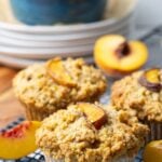 Close up of sourdough peach cobbler muffins with streusel topping on a wire rack.