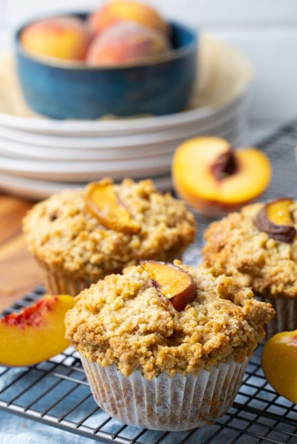Close up of sourdough peach cobbler muffins with streusel topping on a wire rack.
