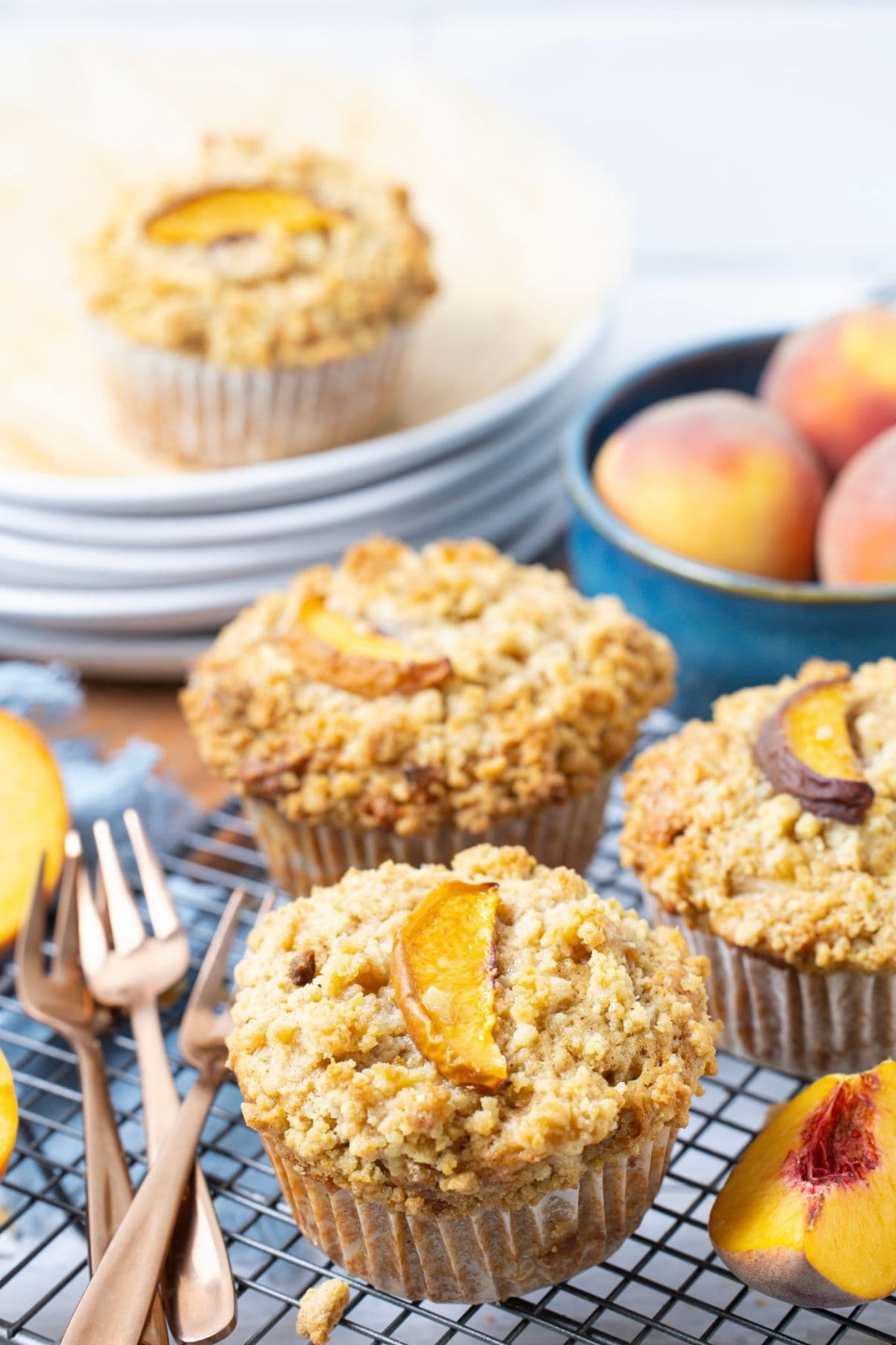 Sourdough peach cobbler muffins on a wire rack next to plates and forks for serving.