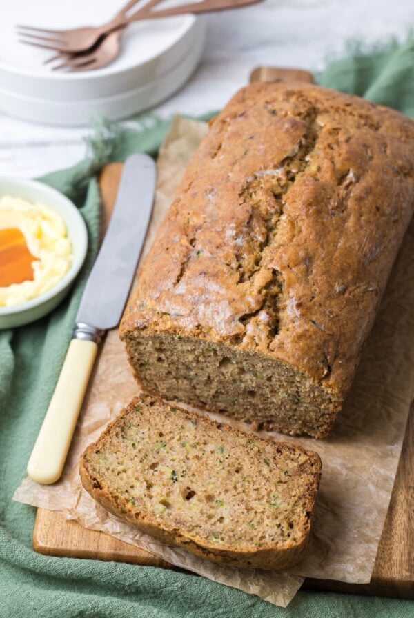 Serving sourdough zucchini bread on a table with a bowl of honey butter for spreading.