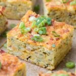 Close up of a piece of sourdough zucchini slice with chopped green onions on top.