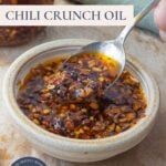Pinterest image with text overlay for homemade chili crunch oil featuring crispy garlic chili oil in a bowl.