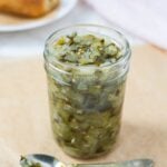 Dill pickle relish in a jar with some on a spoon for serving.