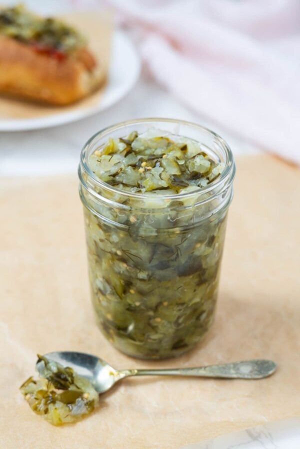 Dill pickle relish in a jar with some on a spoon for serving.