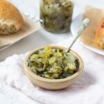 Close up of dill pickle relish in a serving bowl with a spoon.