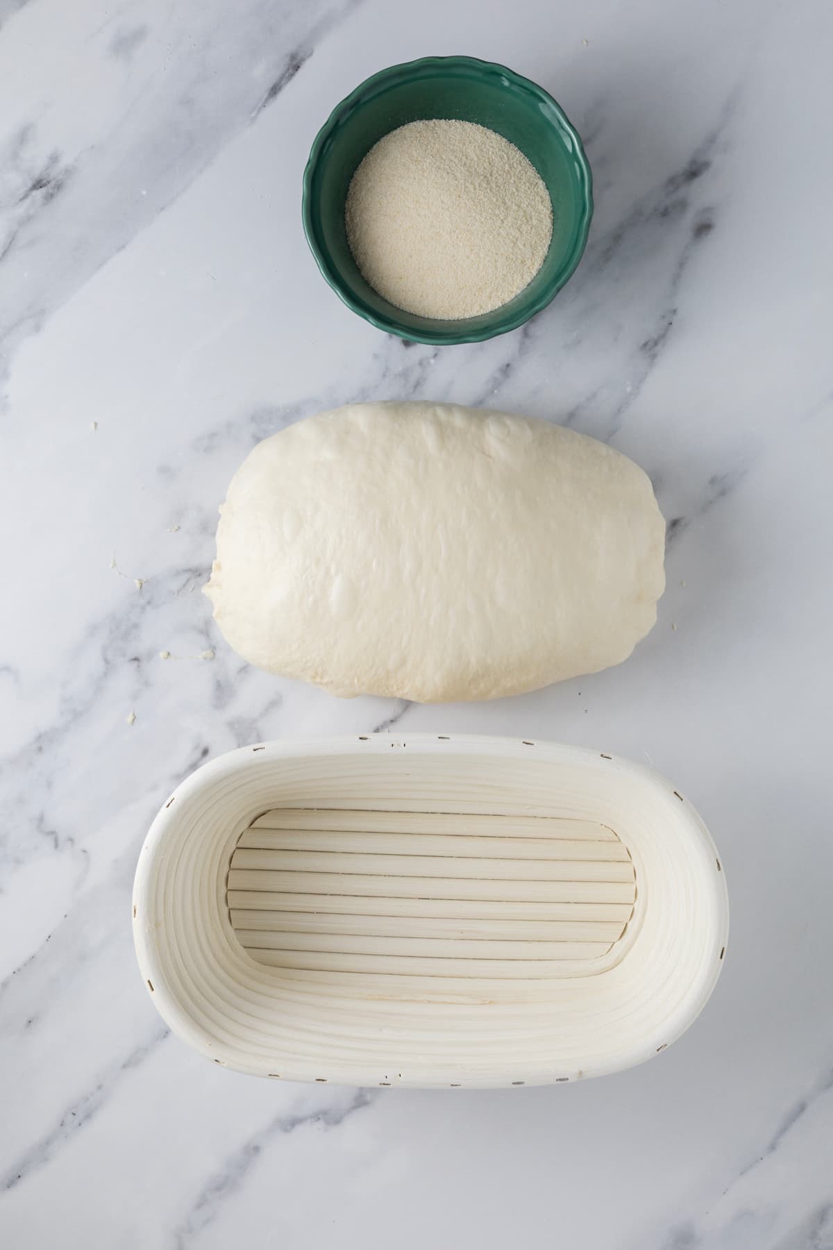 Shaped overnight sourdough bread dough beside a banneton before proofing.