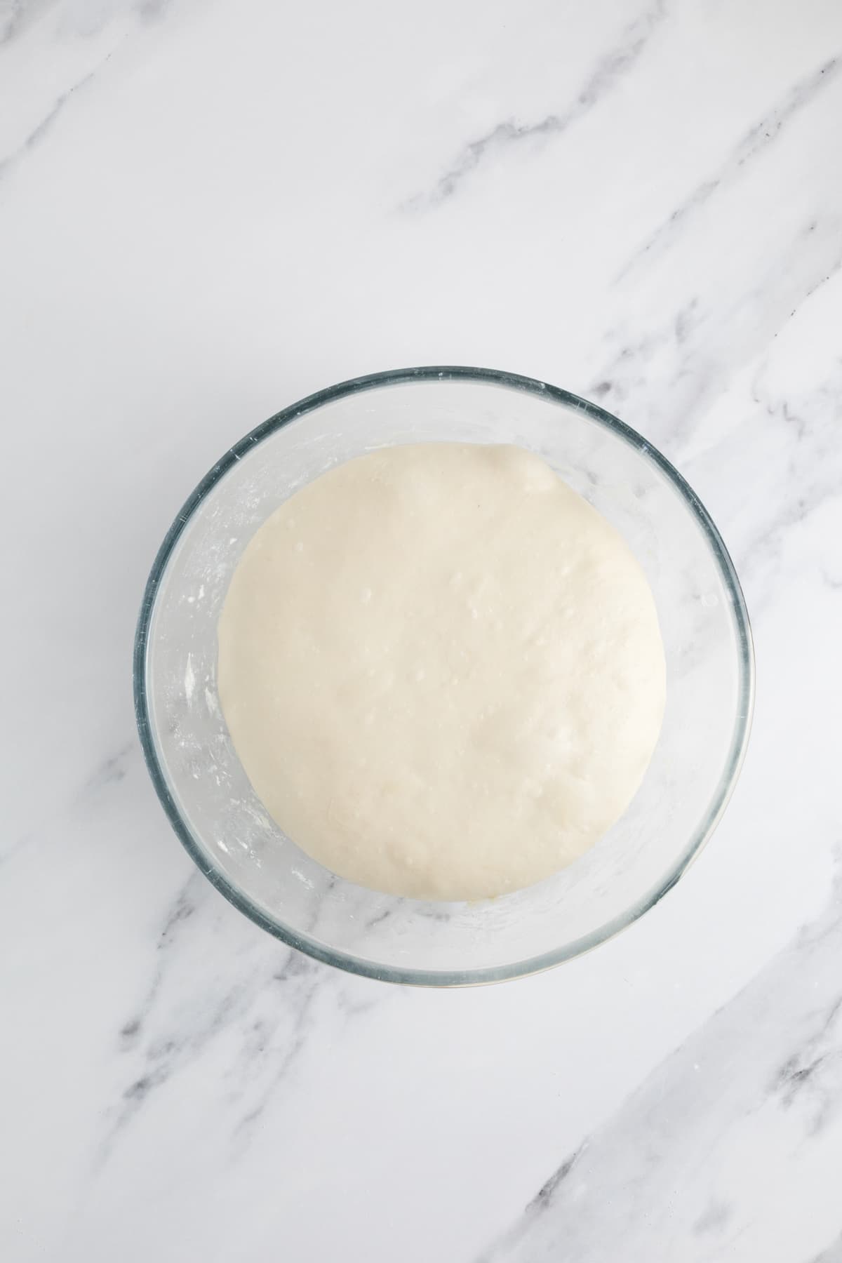 Overnight sourdough bread dough after bulk fermentation in a glass bowl.