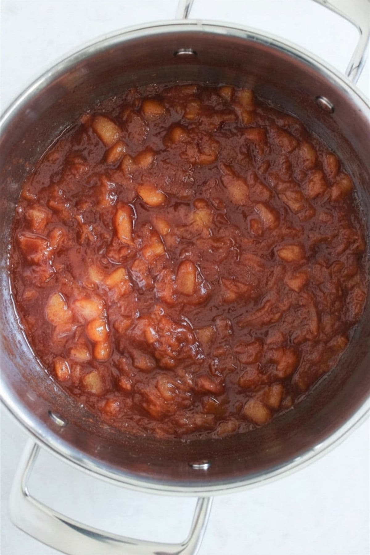 Peach cobbler jam ingredients simmered together in a saucepan until thick and jammy.