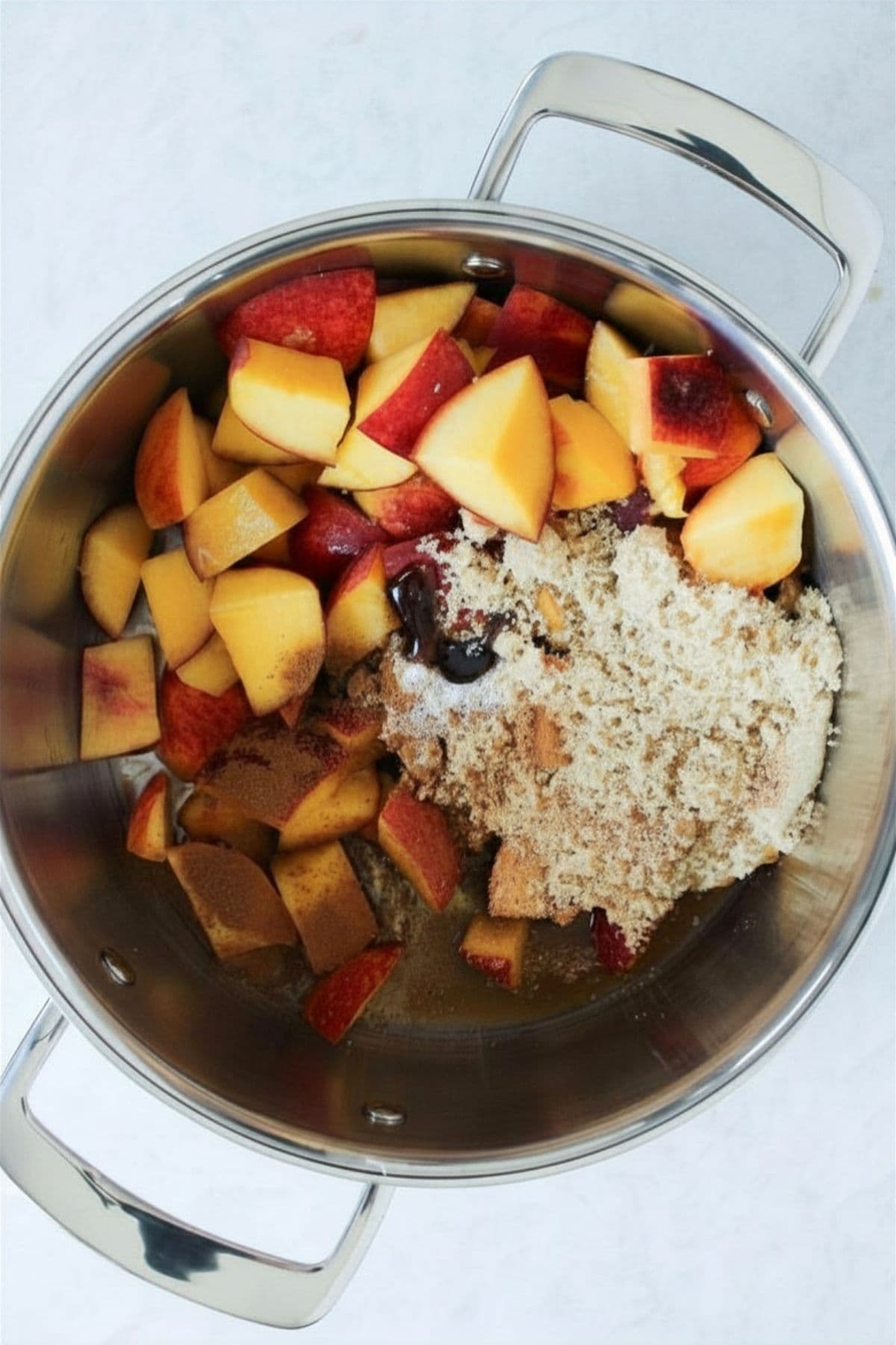 Fresh peaches, brown sugar, spices, and vanilla added to a saucepan to begin making peach cobbler jam.