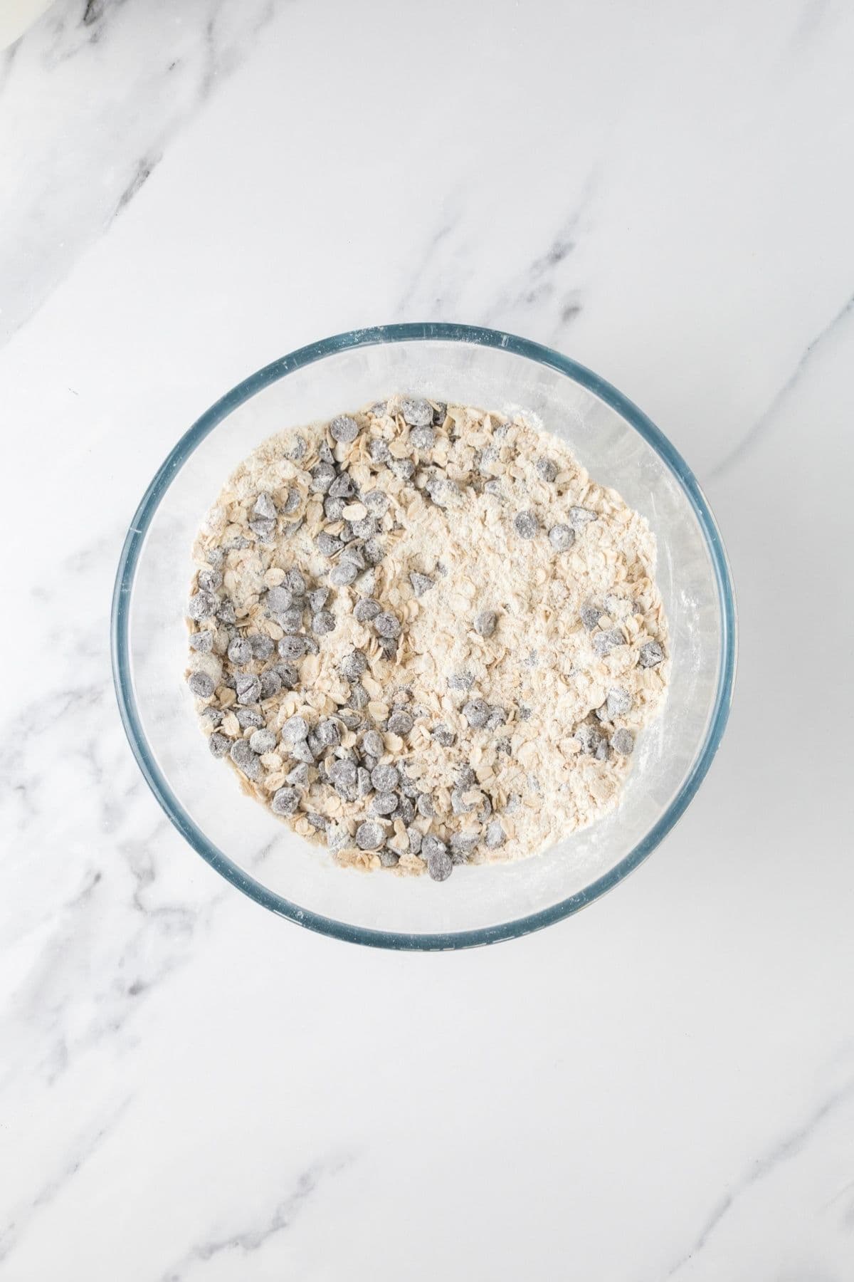 Mixing the dry ingredients in a glass bowl to make protein sourdough chocolate chip cookies.