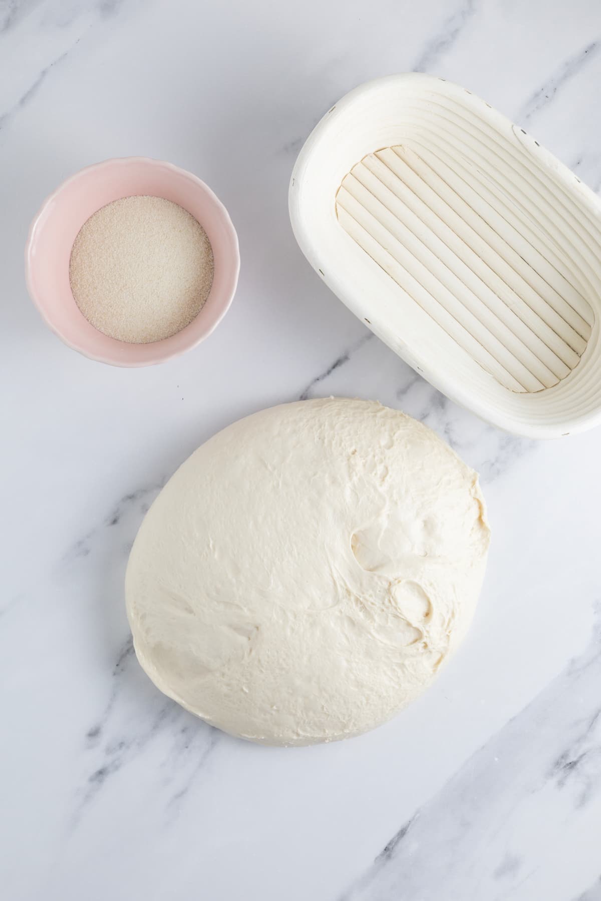 Same day sourdough bread dough on counter next to semolina flour and an oval banneton to begin shaping.