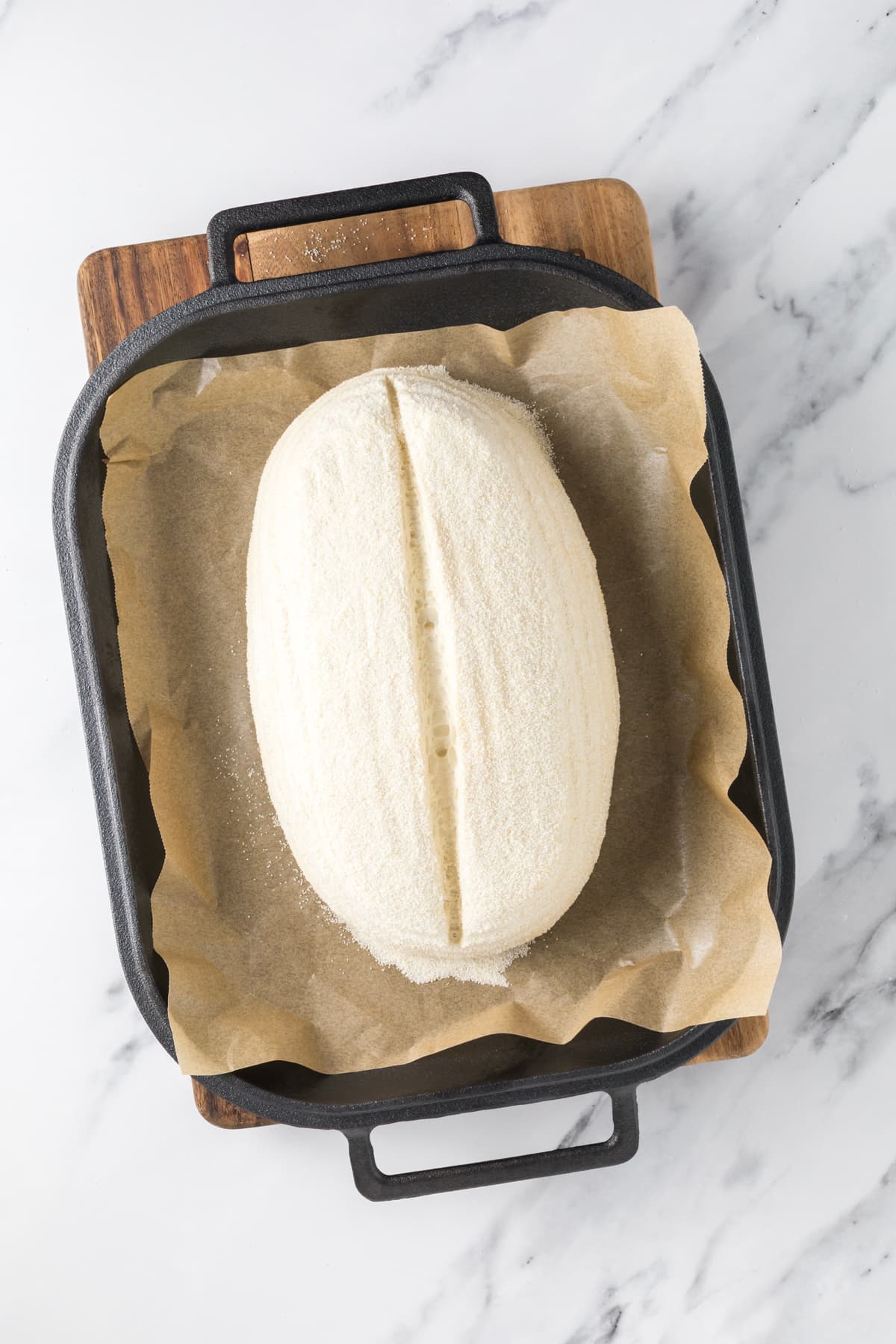 Proofed same day sourdough dough scored and ready to bake in a cast iron baker.